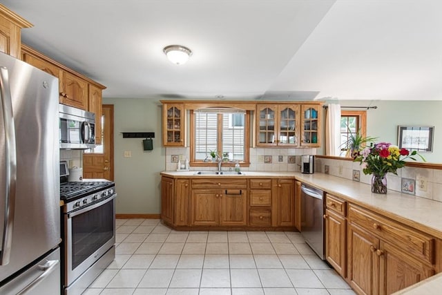 kitchen featuring appliances with stainless steel finishes, a sink, plenty of natural light, and tasteful backsplash