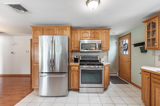 kitchen with stainless steel appliances, a baseboard radiator, glass insert cabinets, light countertops, and decorative backsplash
