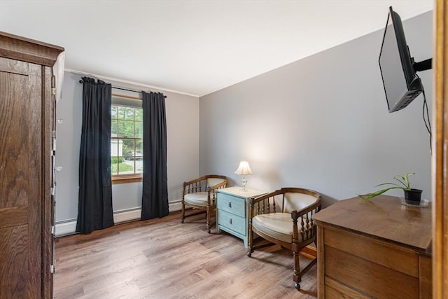sitting room with light wood-style floors, crown molding, a baseboard radiator, and baseboards