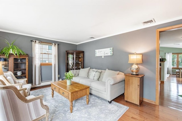 living area with wood finished floors, ornamental molding, and baseboards