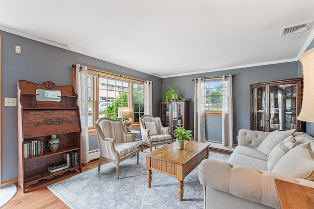 living area featuring healthy amount of natural light, crown molding, wood finished floors, baseboard heating, and baseboards