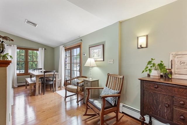 sitting room featuring vaulted ceiling, baseboard heating, and light wood-style floors