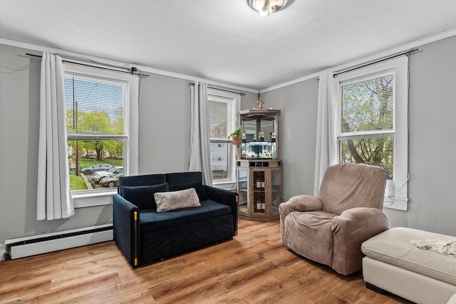 sitting room with a healthy amount of sunlight, ornamental molding, a baseboard heating unit, and wood finished floors