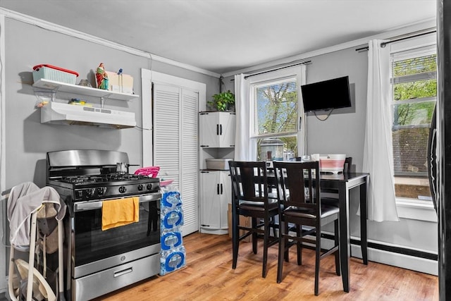 kitchen with crown molding, under cabinet range hood, stainless steel gas stove, and a healthy amount of sunlight