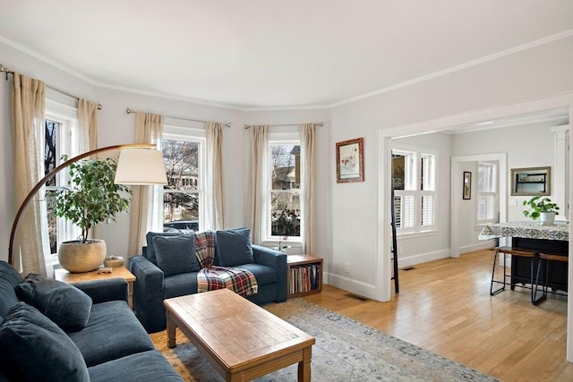 living area featuring visible vents, baseboards, light wood-style floors, and crown molding