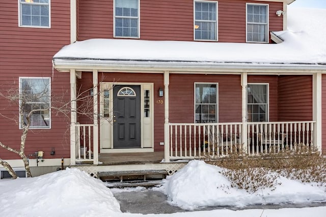 snow covered property entrance featuring covered porch