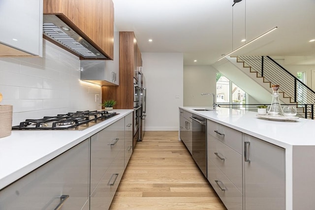 95 Griswold St Unit 95, Cambridge, MA 02139 - kitchen with modern cabinets, wall chimney range hood, a sink, stainless steel appliances, and gray cabinetry