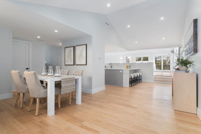 dining area with vaulted ceiling, sink, and light hardwood / wood-style floors