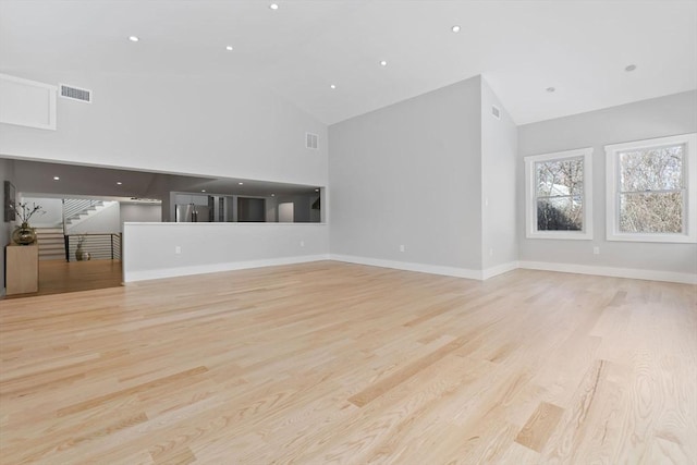 unfurnished living room with high vaulted ceiling and light hardwood / wood-style floors