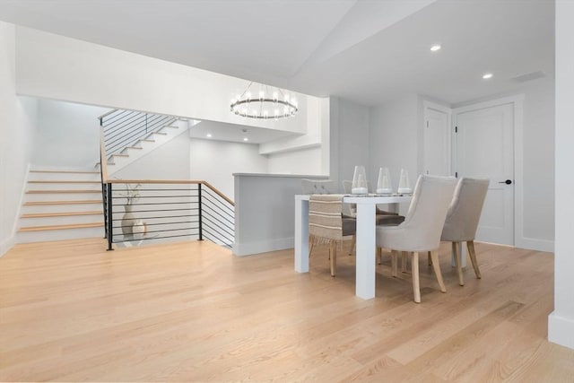 dining space featuring vaulted ceiling, light wood-type flooring, and an inviting chandelier