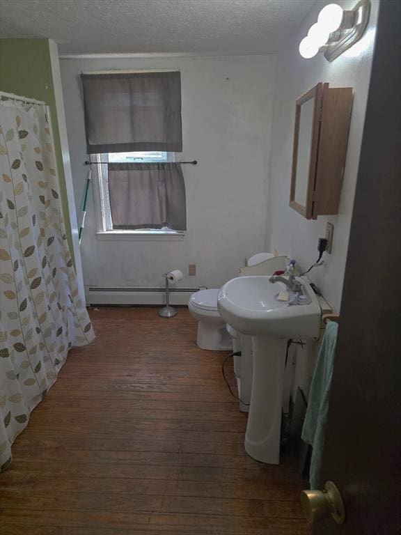 bathroom with a baseboard heating unit, hardwood / wood-style floors, a textured ceiling, toilet, and a shower with shower curtain