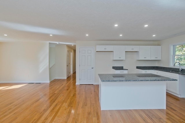 kitchen featuring light wood-type flooring, white cabinetry, a kitchen island, and sink