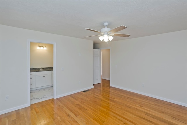 unfurnished room with sink, light hardwood / wood-style flooring, and ceiling fan