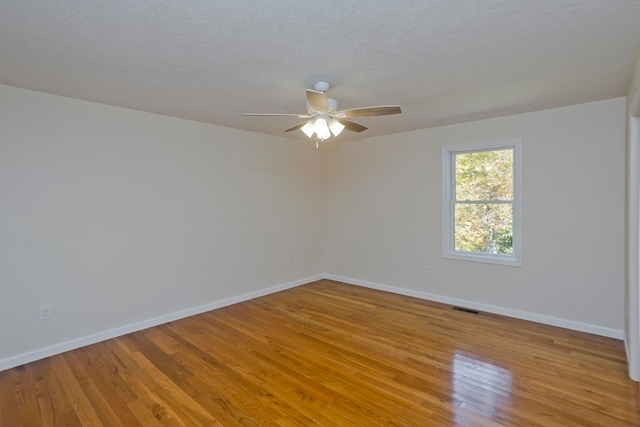 spare room with light hardwood / wood-style flooring, ceiling fan, and a textured ceiling