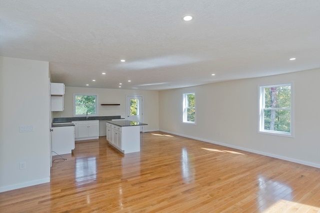 kitchen featuring white cabinetry, light hardwood / wood-style floors, a kitchen island, and sink