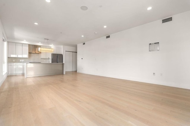 unfurnished living room with light wood finished floors, baseboards, visible vents, and recessed lighting