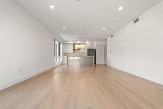 unfurnished living room with light wood-style floors, recessed lighting, visible vents, and baseboards