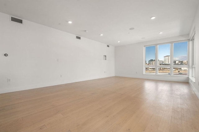 empty room with visible vents, baseboards, light wood-type flooring, and recessed lighting
