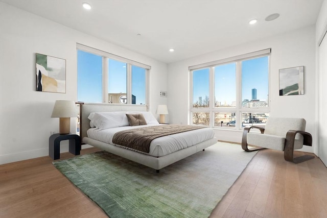 bedroom with a city view, hardwood / wood-style floors, and multiple windows