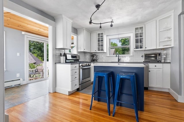 10 Saunders Rd, Lynn, MA 01904 - kitchen featuring stainless steel gas range, baseboard heating, a center island, tasteful backsplash, and white cabinetry
