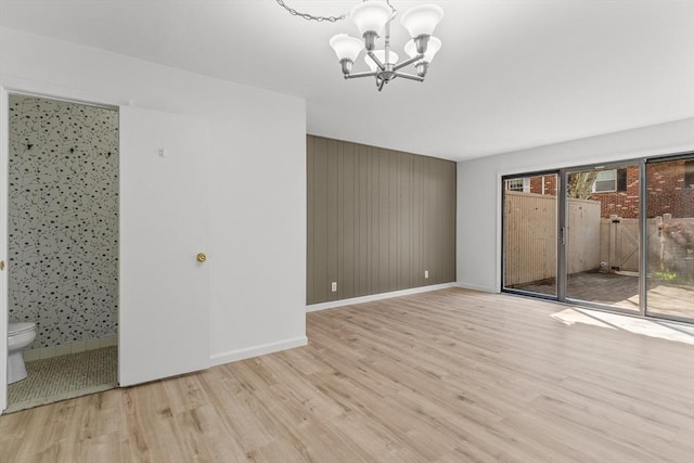 unfurnished bedroom with access to outside, a chandelier, wood finished floors, and baseboards