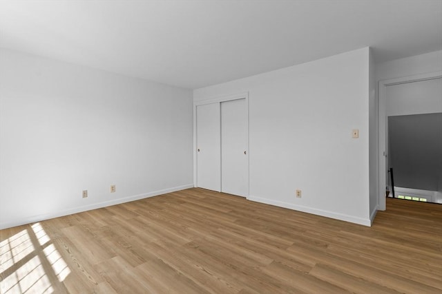 unfurnished bedroom with light wood-style flooring, baseboards, and a closet
