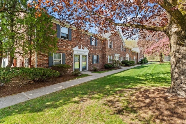 view of property featuring a front yard, brick siding, and a residential view