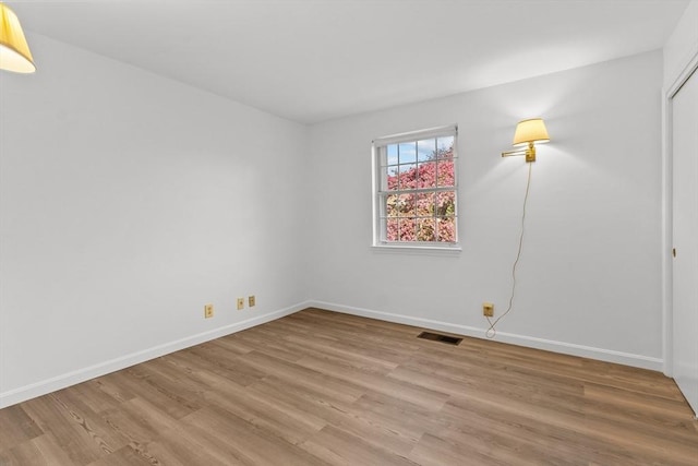 spare room featuring light wood finished floors and baseboards