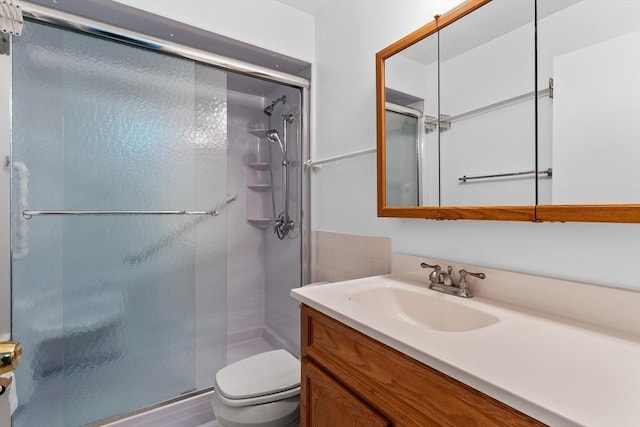 full bath with toilet, vanity, and a shower stall
