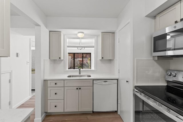 kitchen featuring appliances with stainless steel finishes, a sink, light countertops, and tasteful backsplash