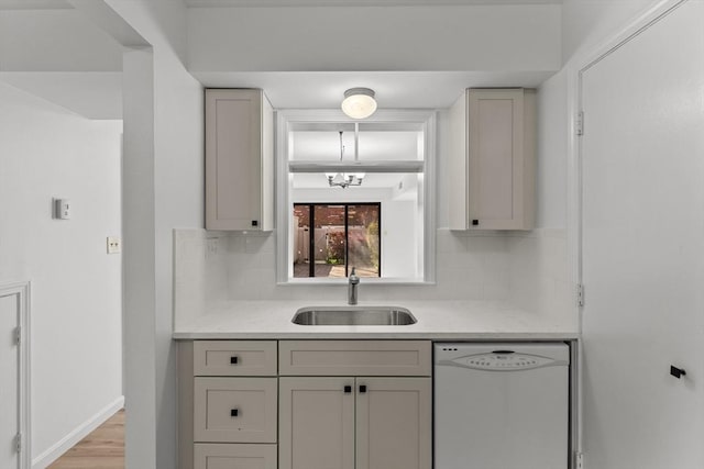 bar area with white dishwasher, a sink, tasteful backsplash, and light wood finished floors