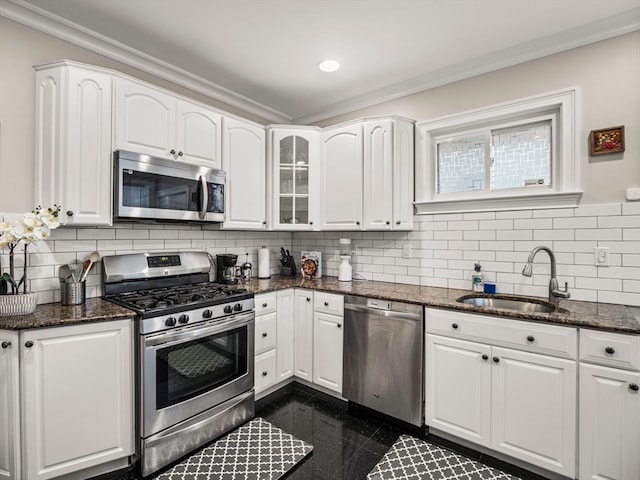 kitchen featuring appliances with stainless steel finishes, dark stone countertops, sink, and tasteful backsplash