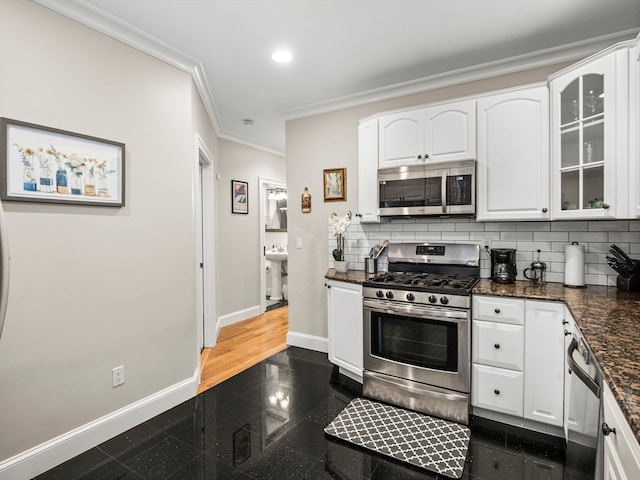 kitchen with dark stone counters, backsplash, ornamental molding, appliances with stainless steel finishes, and dark hardwood / wood-style floors