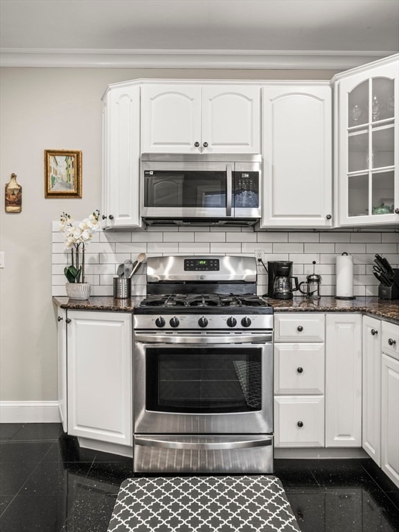 kitchen with stainless steel appliances, tasteful backsplash, dark stone countertops, and white cabinets