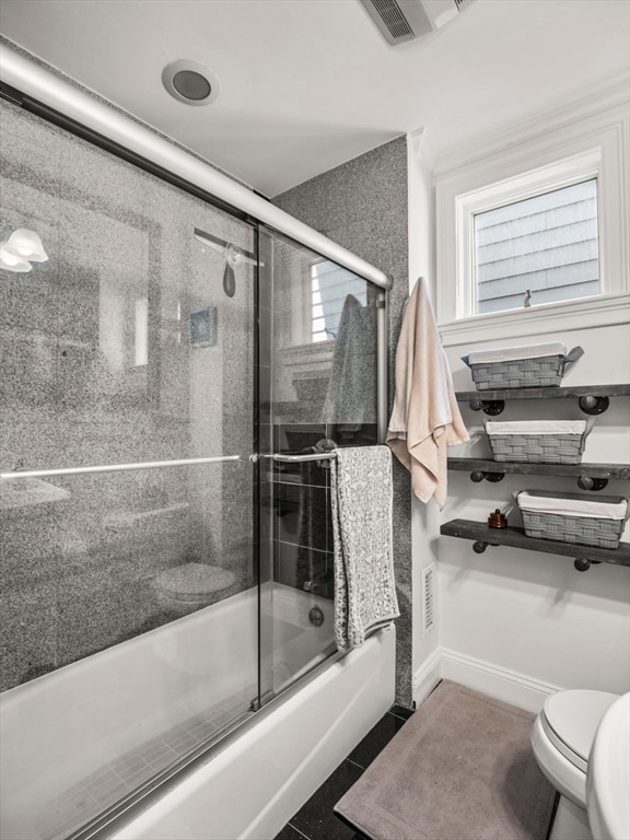 bathroom featuring bath / shower combo with glass door, toilet, and tile patterned flooring