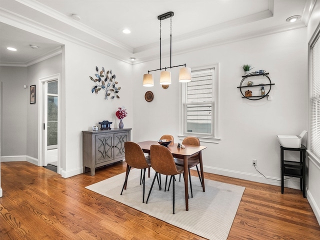 dining room featuring ornamental molding, a tray ceiling, and wood-type flooring