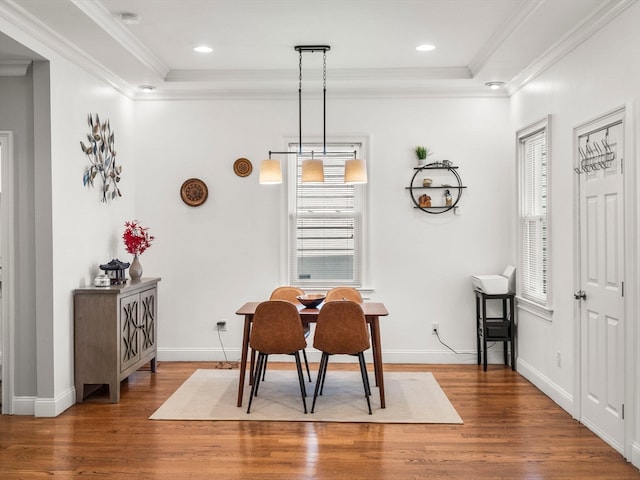 dining area with hardwood / wood-style floors, a raised ceiling, and crown molding