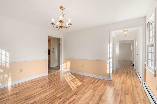 empty room featuring light wood-type flooring, a notable chandelier, and a baseboard heating unit