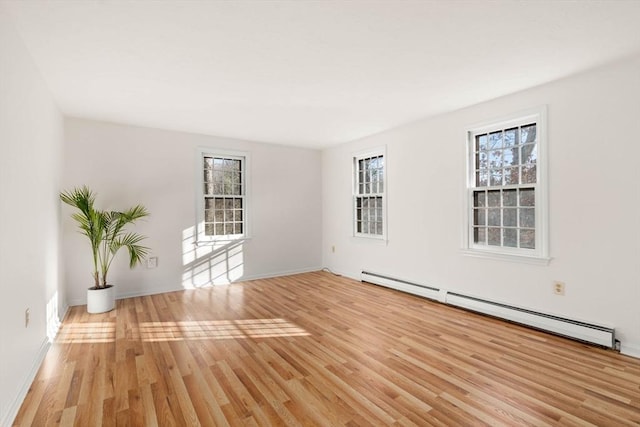 spare room featuring a wealth of natural light, light hardwood / wood-style flooring, and a baseboard heating unit