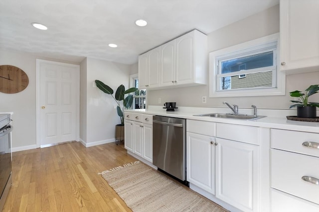 kitchen featuring white cabinets, a sink, dishwasher, baseboards, and a healthy amount of sunlight