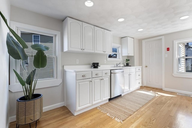kitchen with dishwasher, light countertops, baseboards, white cabinets, and light wood-style floors