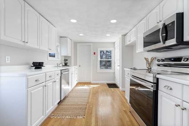 kitchen featuring recessed lighting, light countertops, white cabinetry, a sink, and appliances with stainless steel finishes