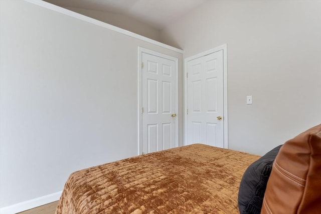 bedroom with baseboards, wood finished floors, and lofted ceiling