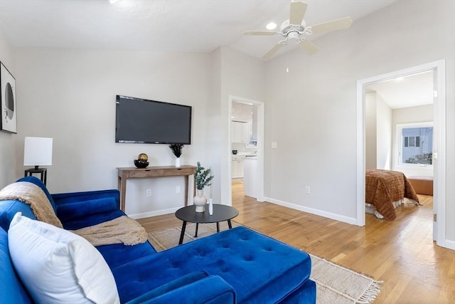 living area with a ceiling fan, baseboards, vaulted ceiling, and wood finished floors