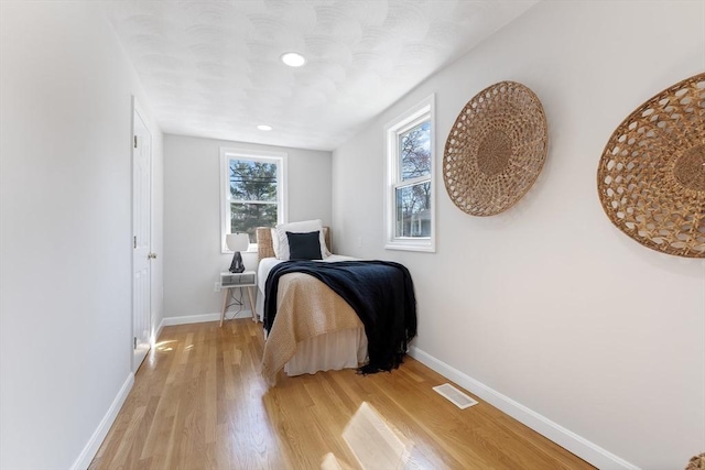 bedroom featuring light wood-type flooring, recessed lighting, baseboards, and visible vents