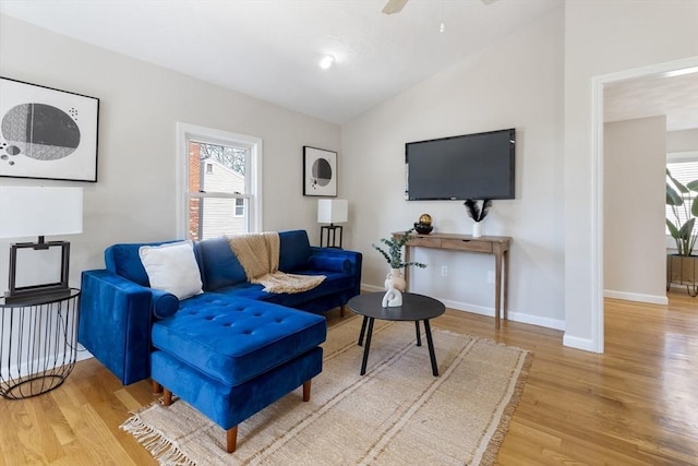 living room featuring a ceiling fan, baseboards, vaulted ceiling, and wood finished floors