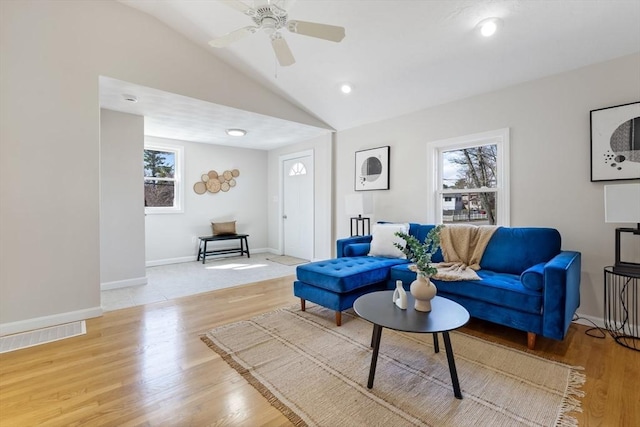 living area featuring visible vents, lofted ceiling, baseboards, a ceiling fan, and light wood-style flooring