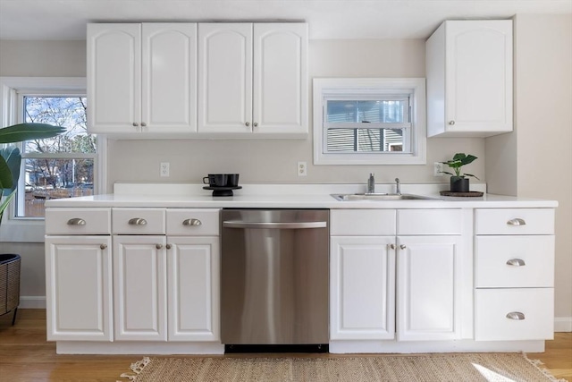 kitchen with stainless steel dishwasher, a sink, and white cabinetry