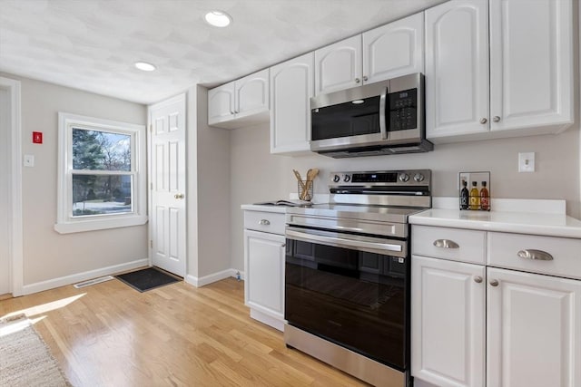 kitchen with appliances with stainless steel finishes, baseboards, and white cabinets