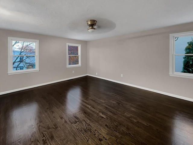 spare room with baseboards and dark wood finished floors